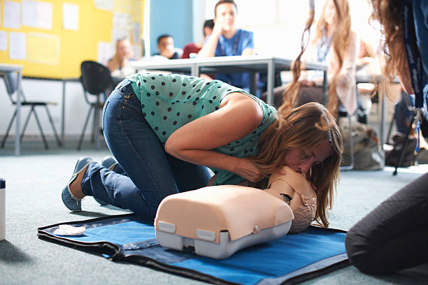 Jeune femme en formation de secourisme qui s'entraîne au bouche à bouche sur un mannequin de secourisme