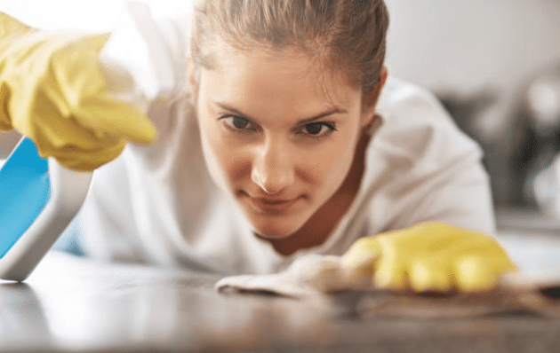 Femme de ménage qui nettoie un plan de travail avec des gants en silicone et un chiffon