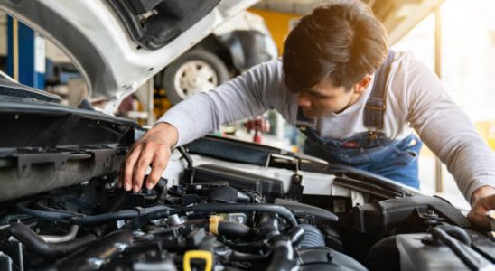 Garagiste qui inspecte le moteur d'une voiture lors de la révision