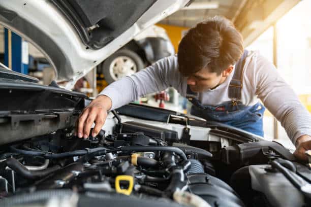 Garagiste qui inspecte le moteur d'une voiture lors de la révision