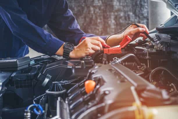 Garagiste en pleine révision sous le capot d'une voiture