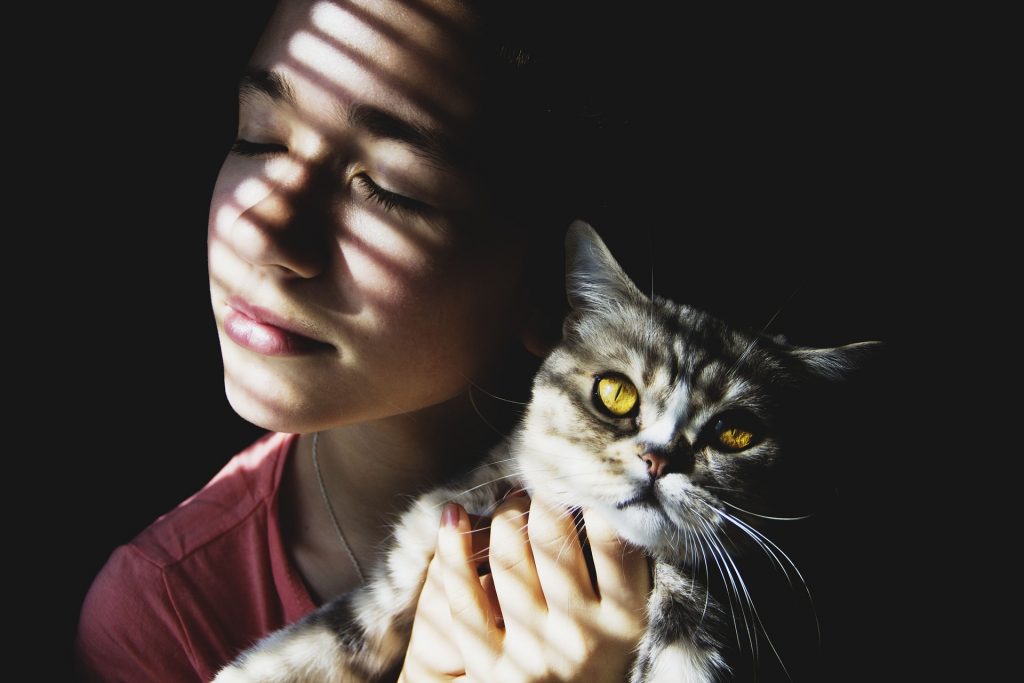 Femme qui tient un chat dans ses bras et lui fait un câlin