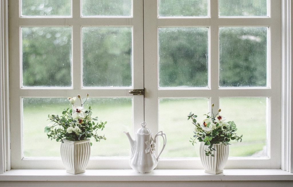 Rebord de fenêtre sur lequel une théière est placée entre deux pots de fleurs 